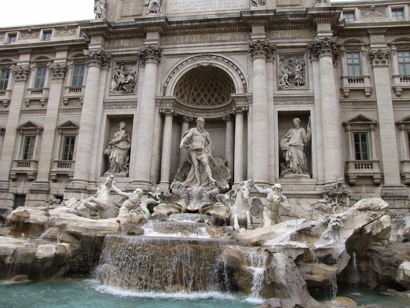 trevi_fontein_beelden.jpg - Het thema van de fontein is de oceaan. Neptunus word op z'n schelpvormige strijdwagen door jonge goden (tritons) met paarden naar de oceaan getrokken. Één paard is wild, de andere rustig. De twee gezichten van de oceaan. De beelden links en rechts van Neptunus beelden overvloed en gezondheid uit.